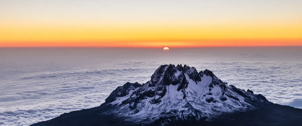 Snow-dusted peak rising above a sea of clouds at sunrise