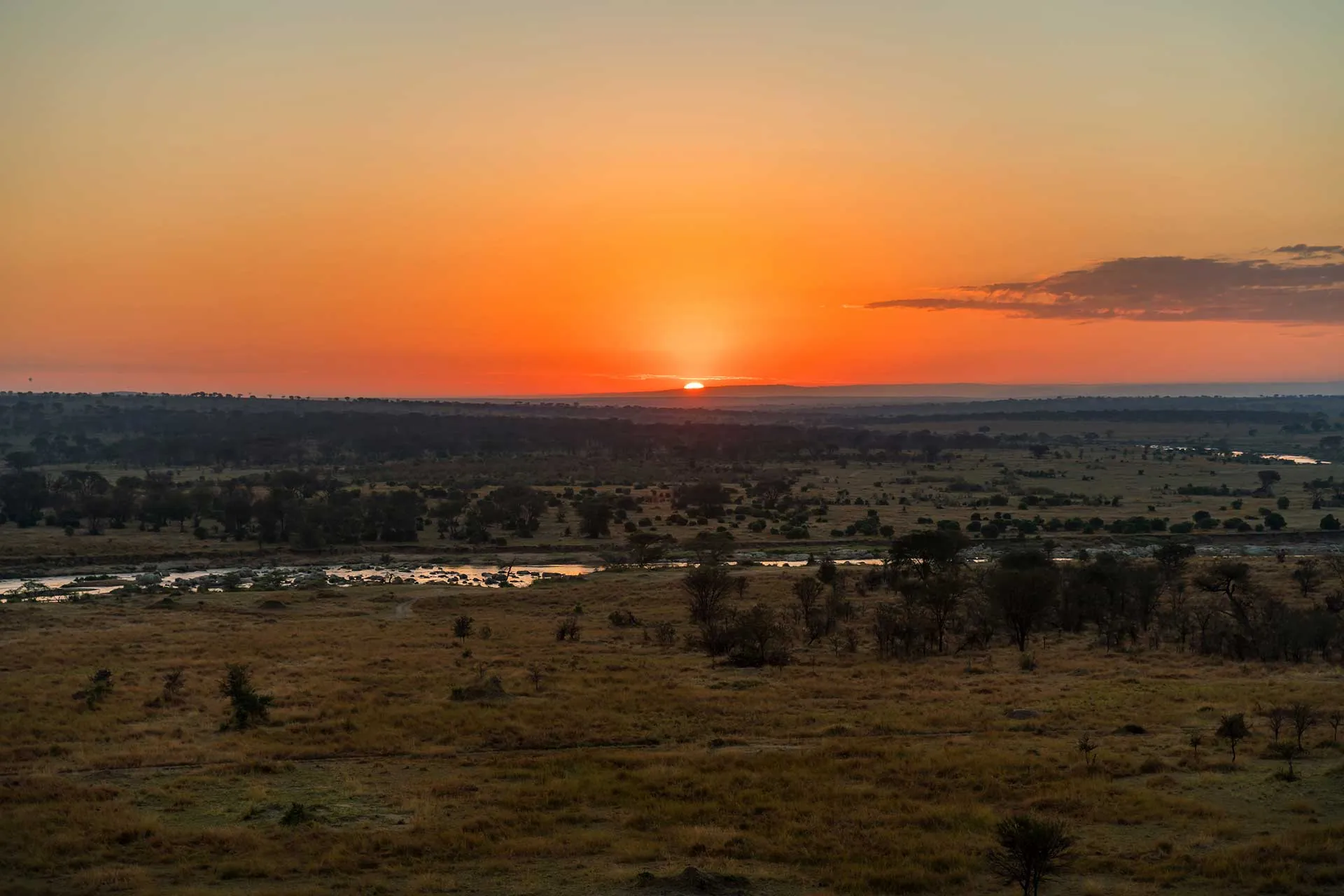 Sun setting over wooded plains and a winding river