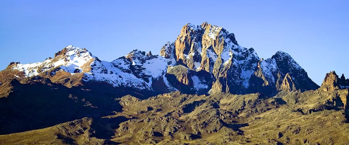 Snow-dusted ridges of Mount Kenya against a blue sky